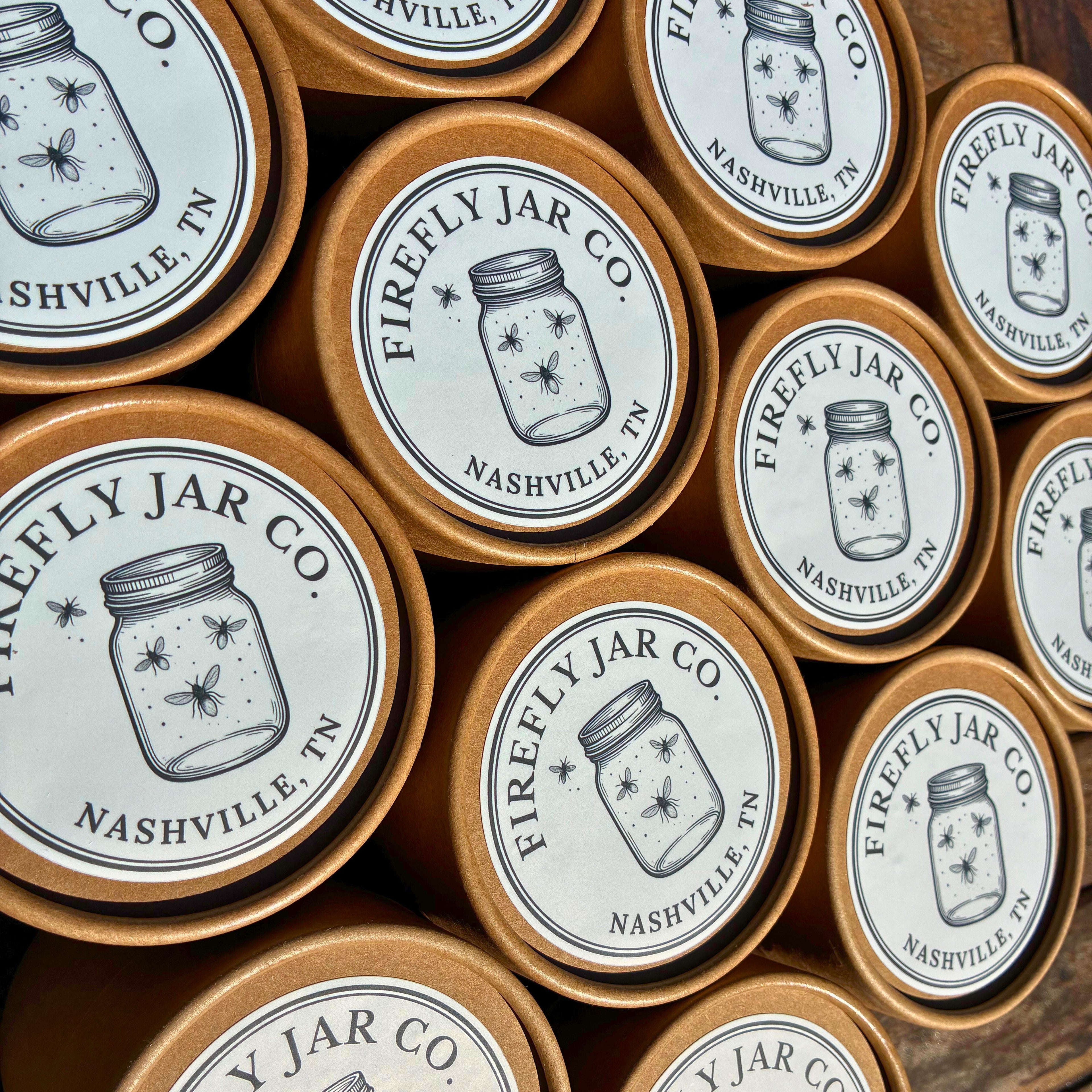 Collection of Firefly Jar Co. jars with labels on a wooden surface