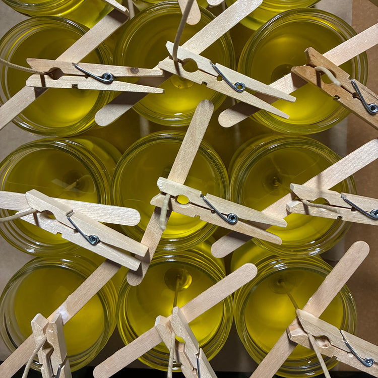 Jars of a yellow substance with wooden clothespins on a cardboard background